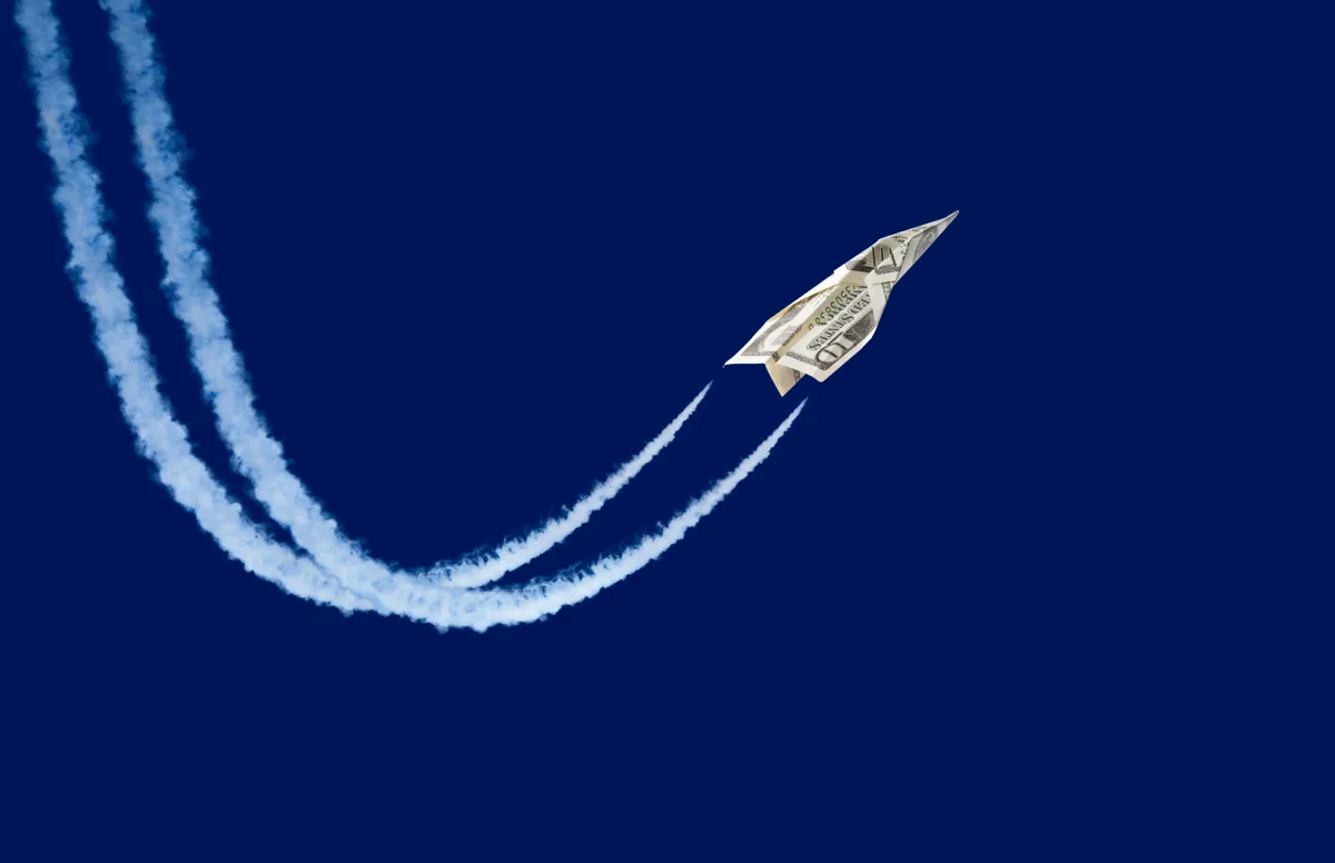 Dollar shaped paper airplane flying up