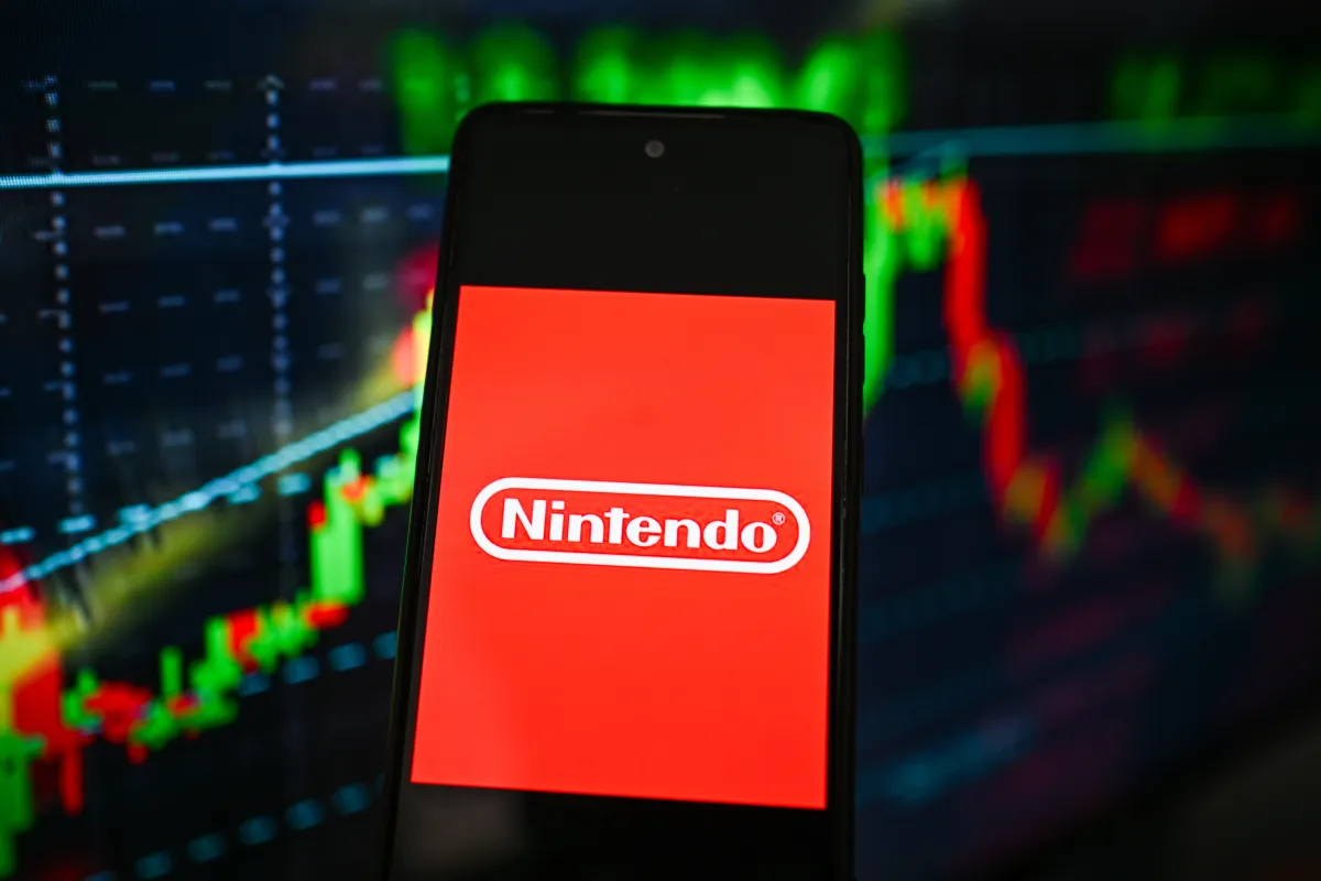 Nintendo logo is seen displayed on a smartphone with stock market percentages on the background.